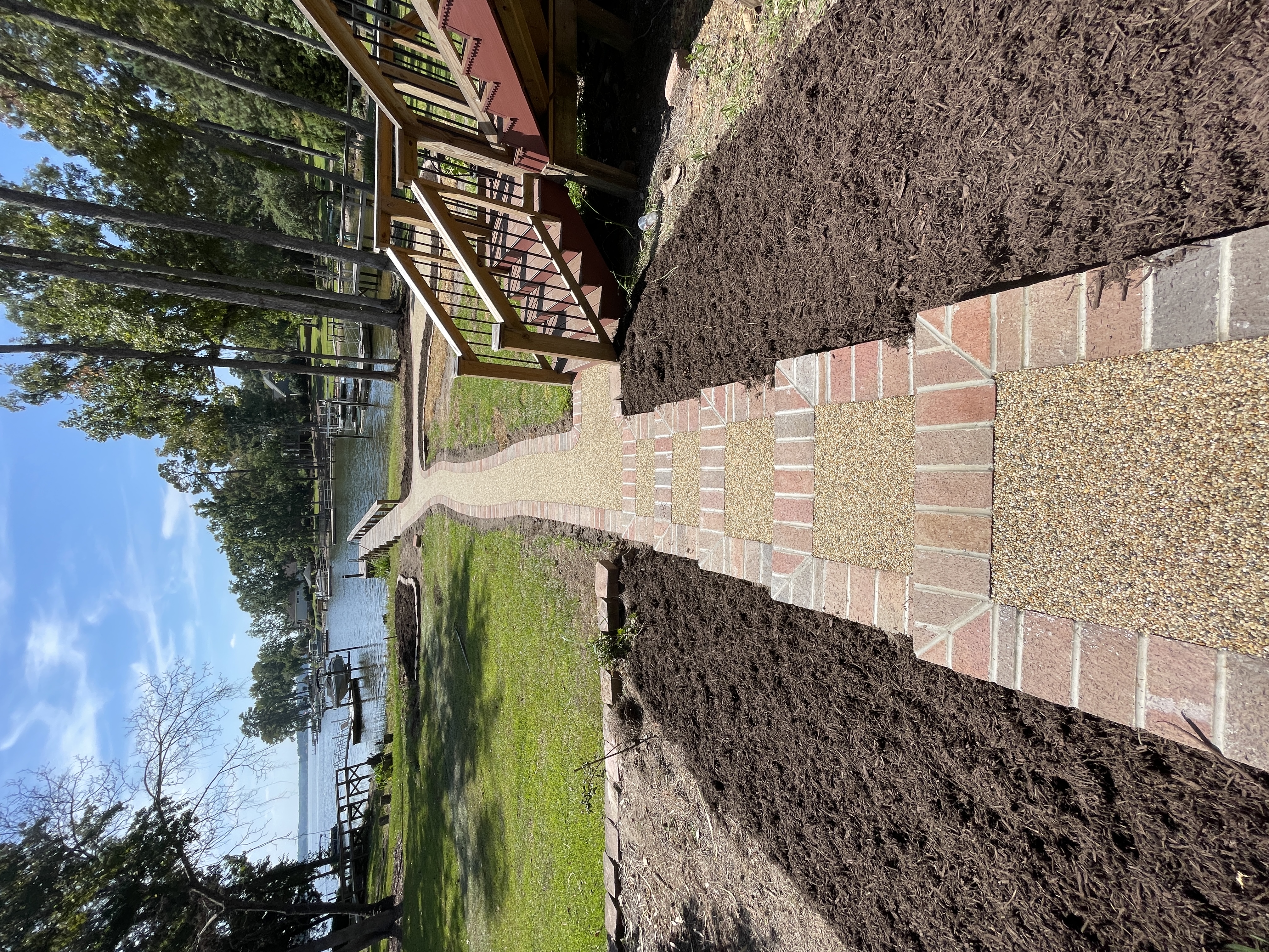 Brick-bordered resin rock walkway leading to lakefront dock